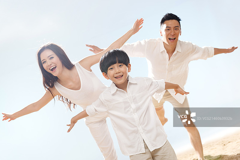 快乐的一家三口在海边玩耍图片素材