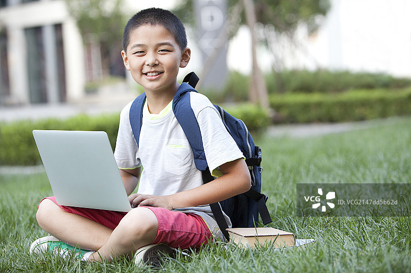 男生坐在草坪上用电脑图片素材