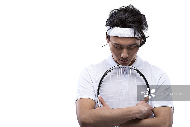 Young man holding tennis racquet, looking down图片素材
