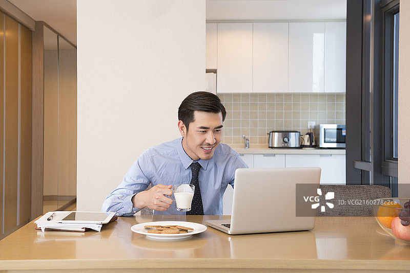 Young man using laptop at breakfast图片素材