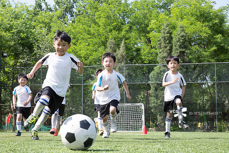 男孩们在球场上踢足球图片素材