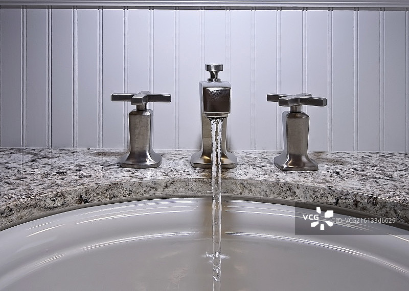 Close-up of faucets and running water in bathroom图片素材