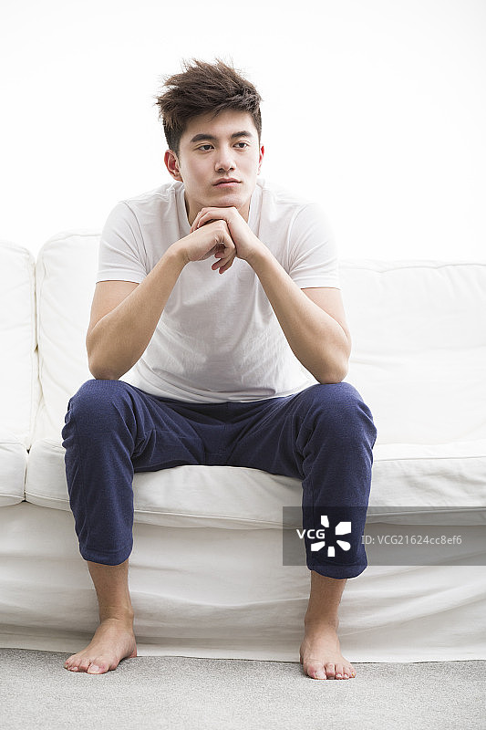 年轻男子在沙发上想事情图片素材