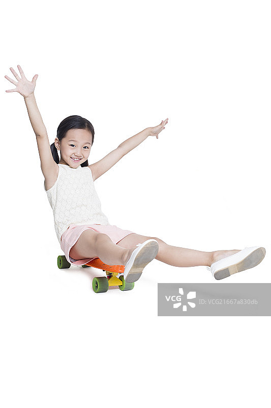 小女孩坐在滑板上玩图片素材
