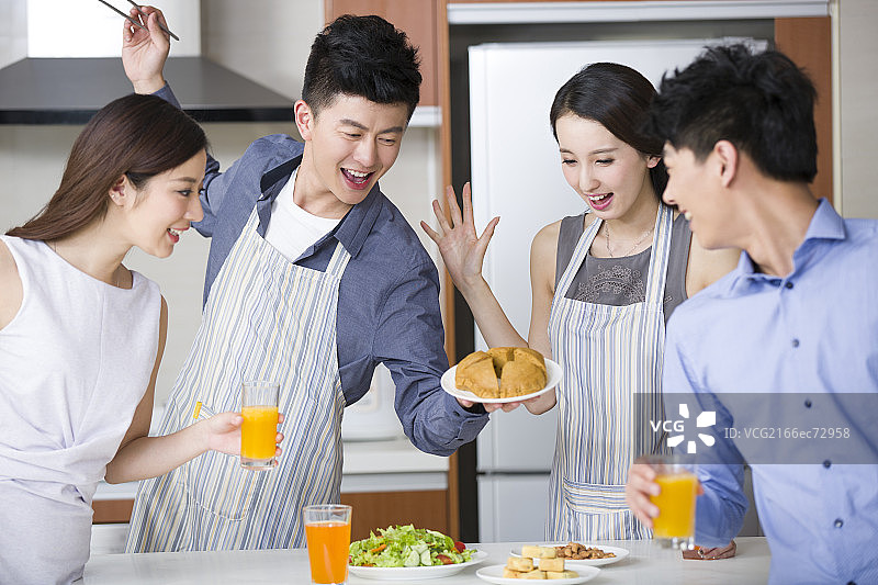 年轻情侣在厨房为朋友做饭图片素材