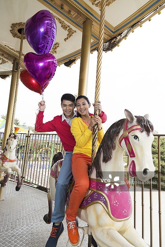 年轻情侣去游乐园骑旋转木马图片素材