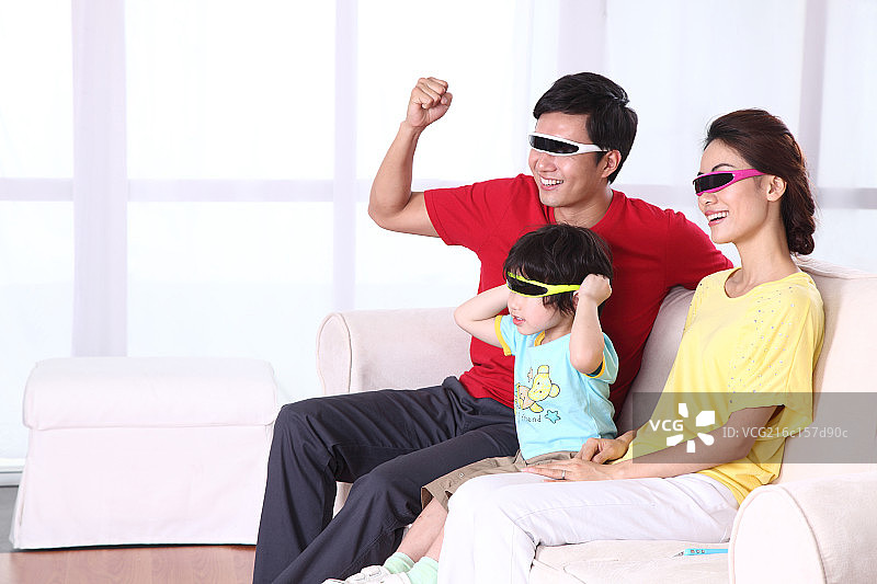 带着3D眼镜看电视的一家三口图片素材