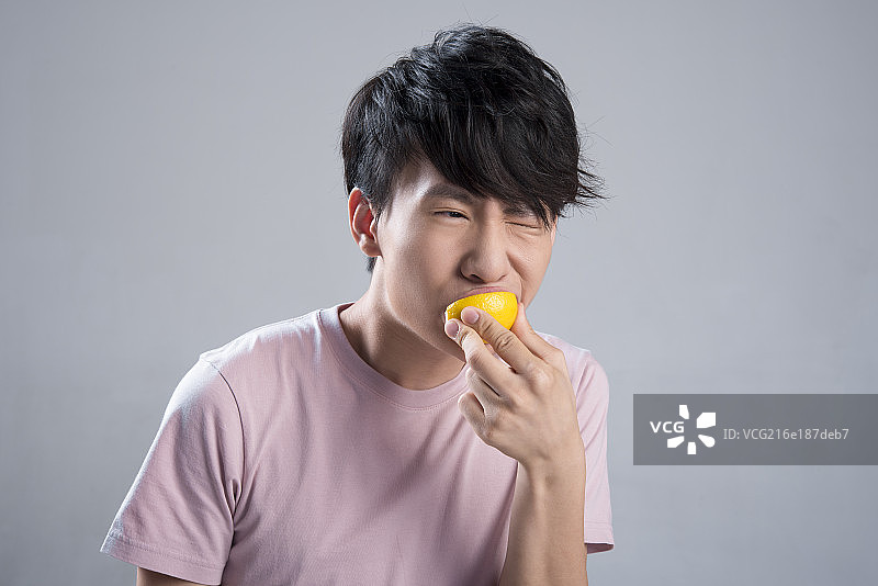 Young man eating lemon图片素材