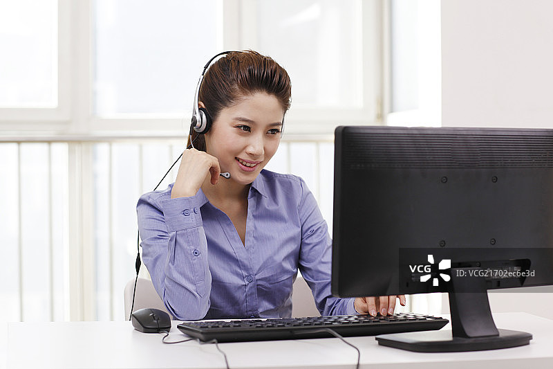 商务女士头戴耳机使用台式电脑图片素材