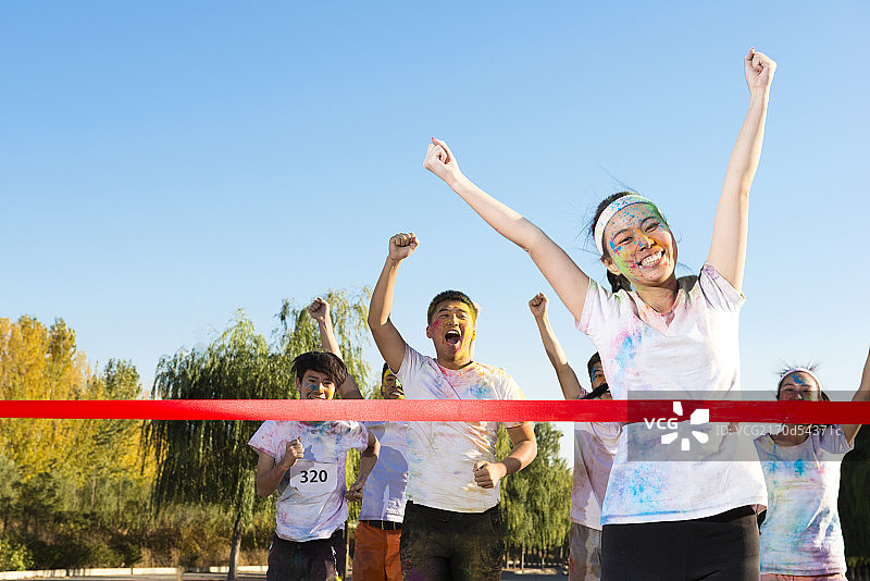 Young woman crossing finishing line at The Color Run图片素材