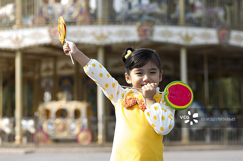 小女孩拿着棒棒糖在游乐园图片素材