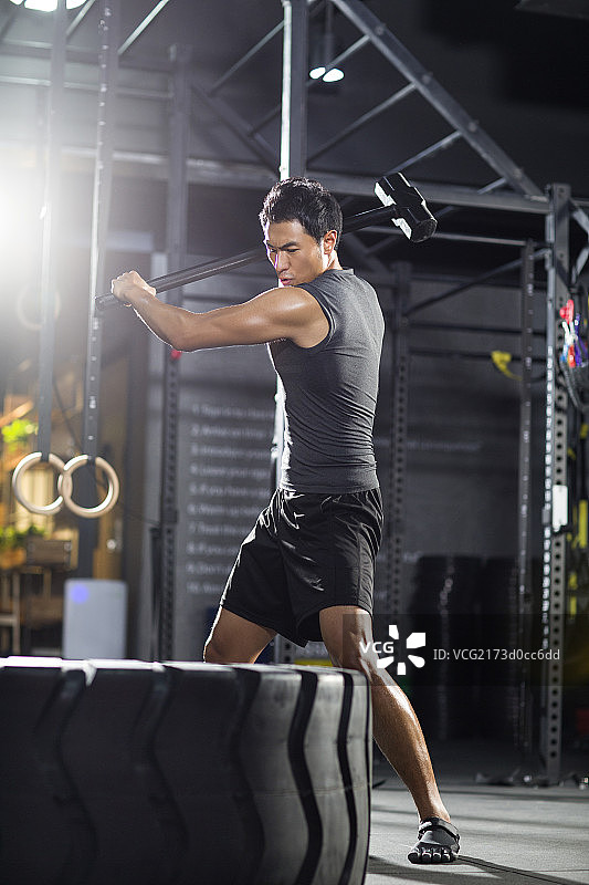 年轻男子在健身房锤击大轮胎图片素材