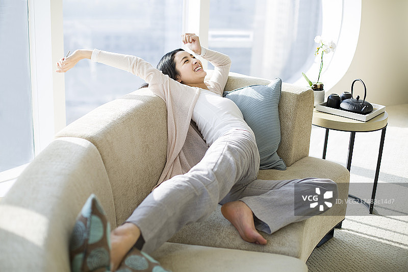 年轻女子在沙发上伸懒腰图片素材