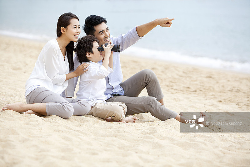 快乐一家人在沙滩上用望远镜看远方图片素材