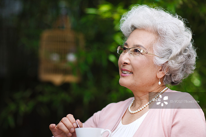 老年女人在庭院里喝咖啡图片素材