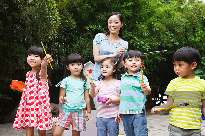 幼儿园里的老师和儿童在户外拿着画笔图片素材