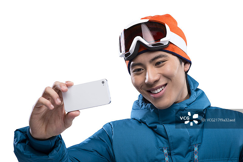 Young man taking selfie with smartphone during skiing图片素材