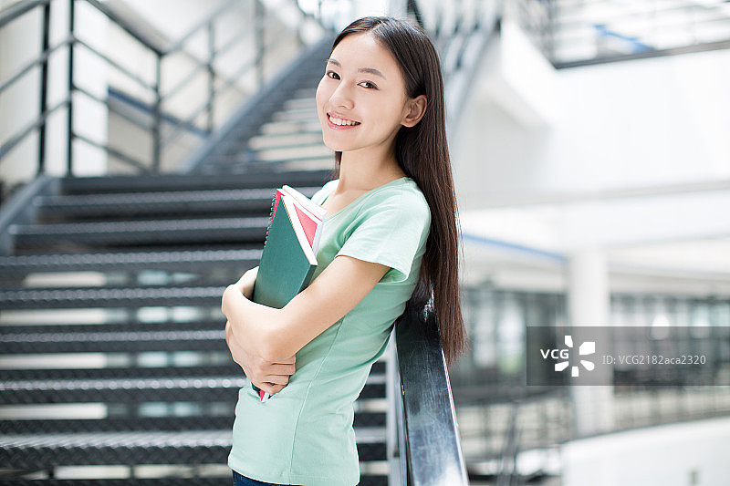 在教学楼里手持书本的女大学生图片素材