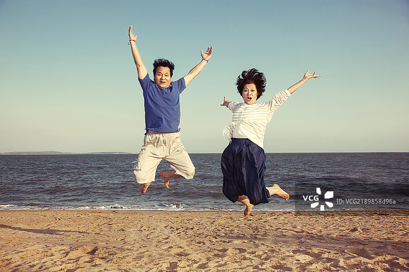 老年夫妻在沙滩上跳跃图片素材