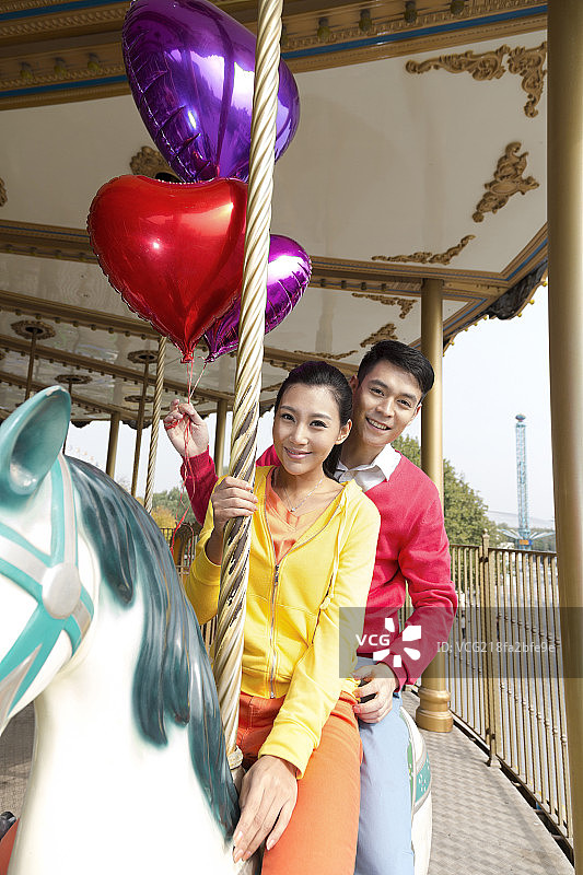 年轻情侣去游乐园骑旋转木马图片素材