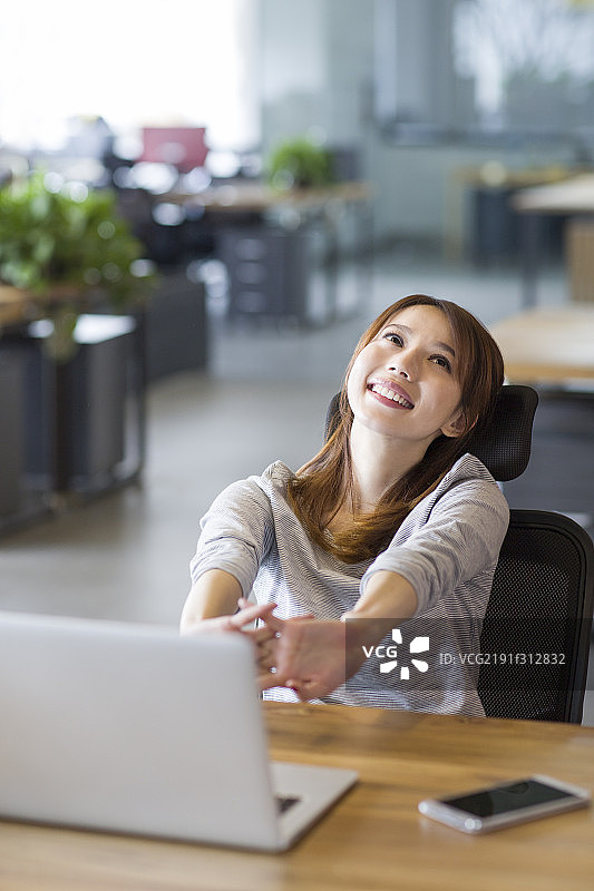 年轻女子在办公室伸懒腰图片素材