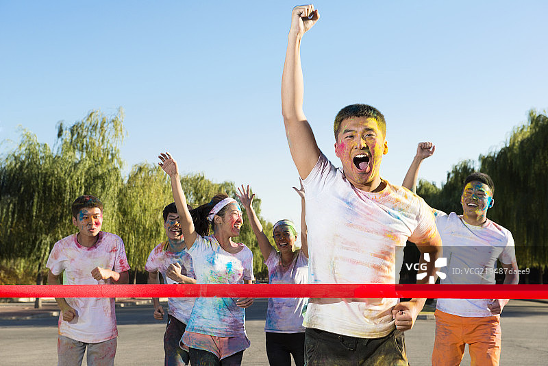 Young man crossing finishing line at The Color Run图片素材