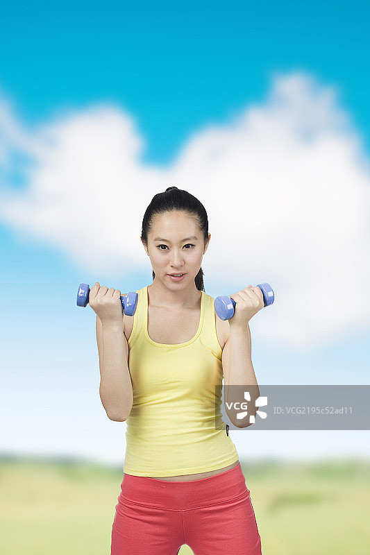 棚拍年轻女人举哑铃图片素材