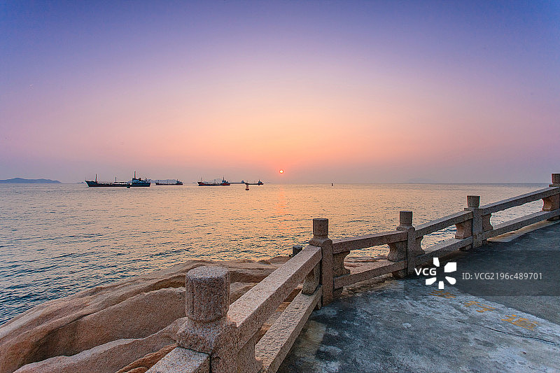 夕阳下的海面船支和海边栈道图片素材