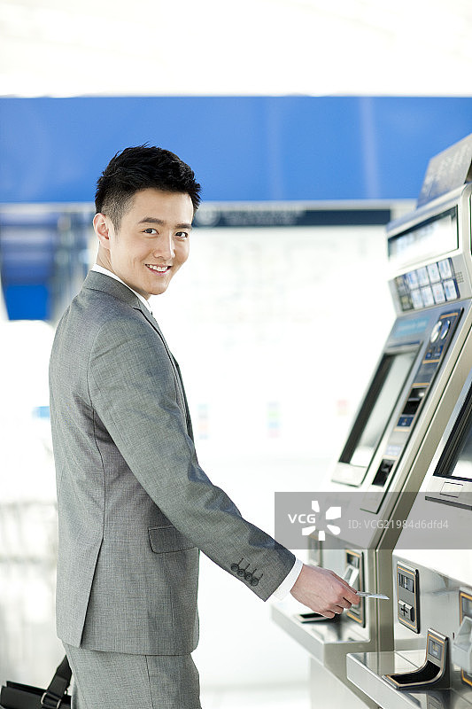 商务男士用自动售票机购票图片素材