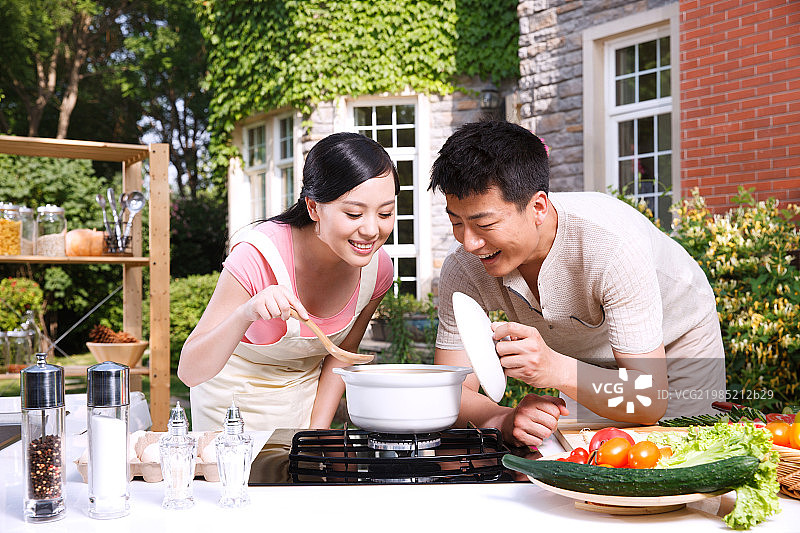 年轻夫妇在户外厨房做饭图片素材