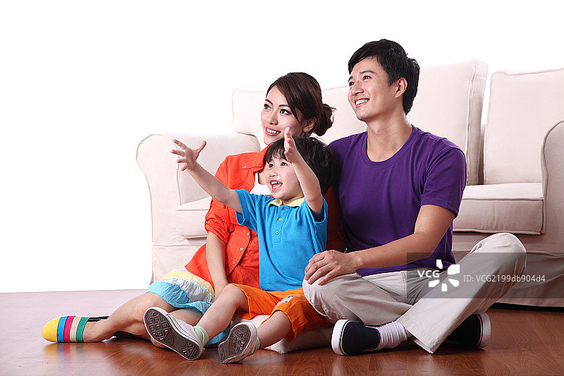 坐在地板上看电视的一家三口图片素材