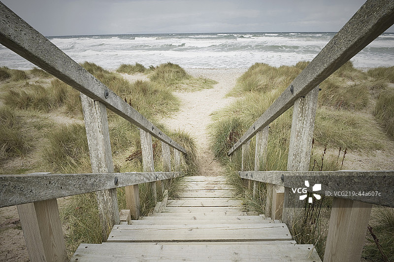 Wooden steps leading down through the dunes onto the shingle beach in winter图片素材