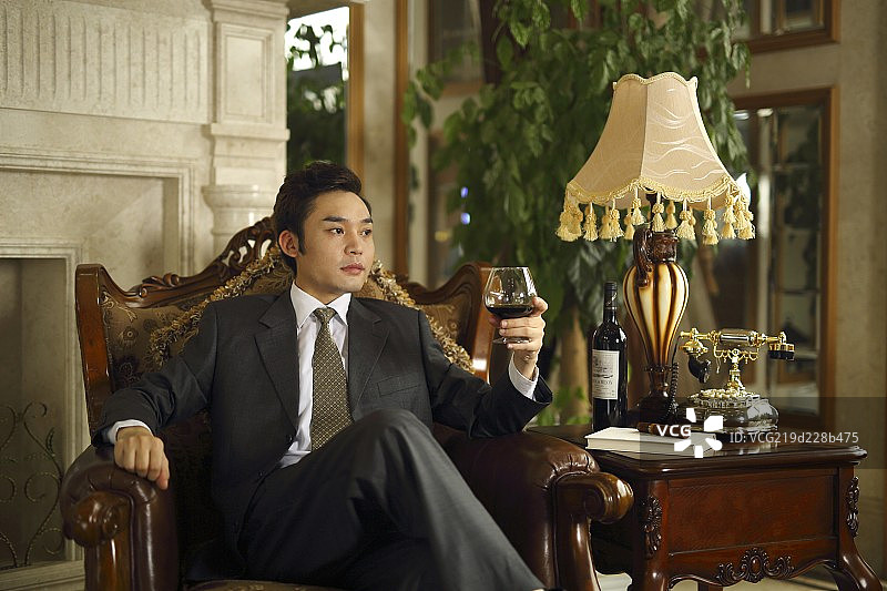 坐在沙发上手拿红酒杯的成功男士图片素材