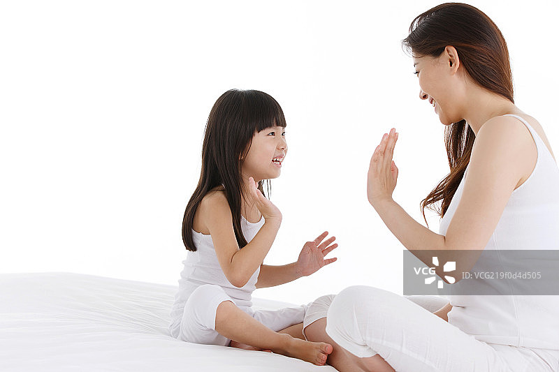 母亲和女儿在卧室的床上玩游戏图片素材