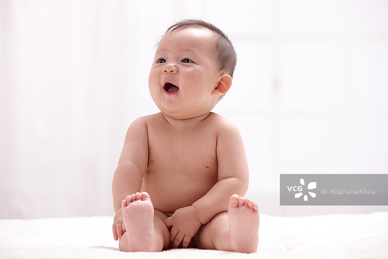 一个婴儿坐在室内床上图片素材