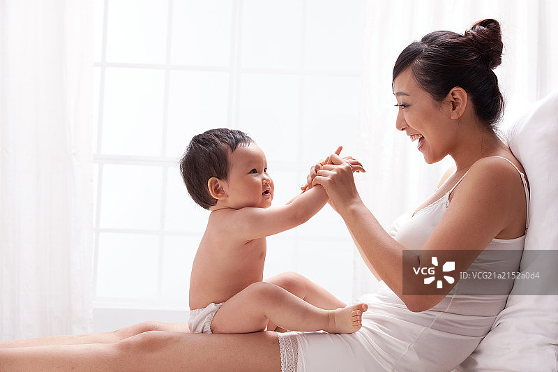 母亲和婴儿面对面坐在床上图片素材