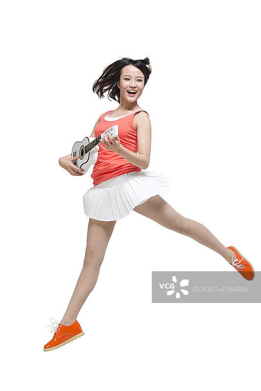 棚拍时尚女青年边弹吉他边唱歌跳舞图片素材