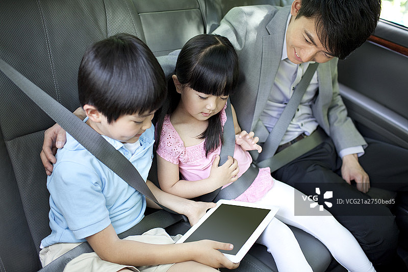 快乐家庭坐在车上玩平板电脑图片素材
