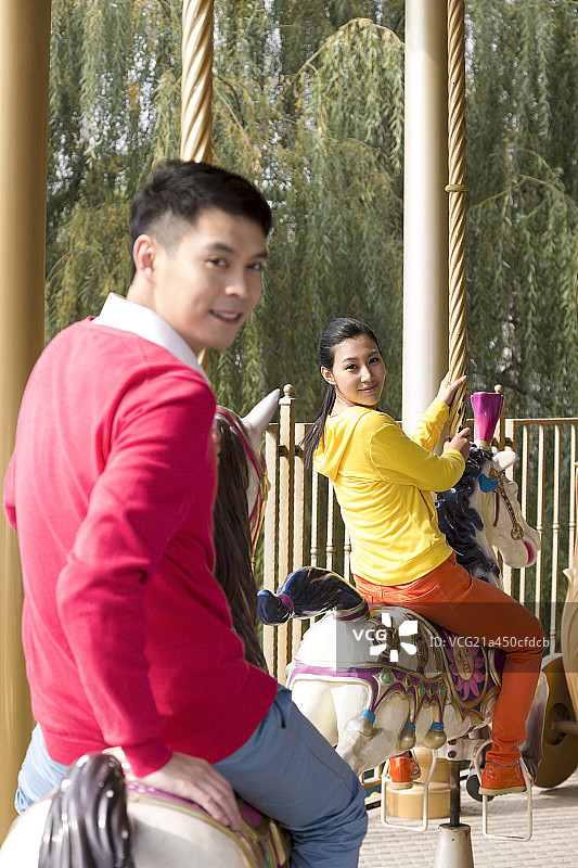 年轻情侣去游乐园骑旋转木马图片素材