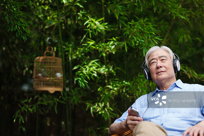 一个老年男人坐在椅子上戴着耳机图片素材
