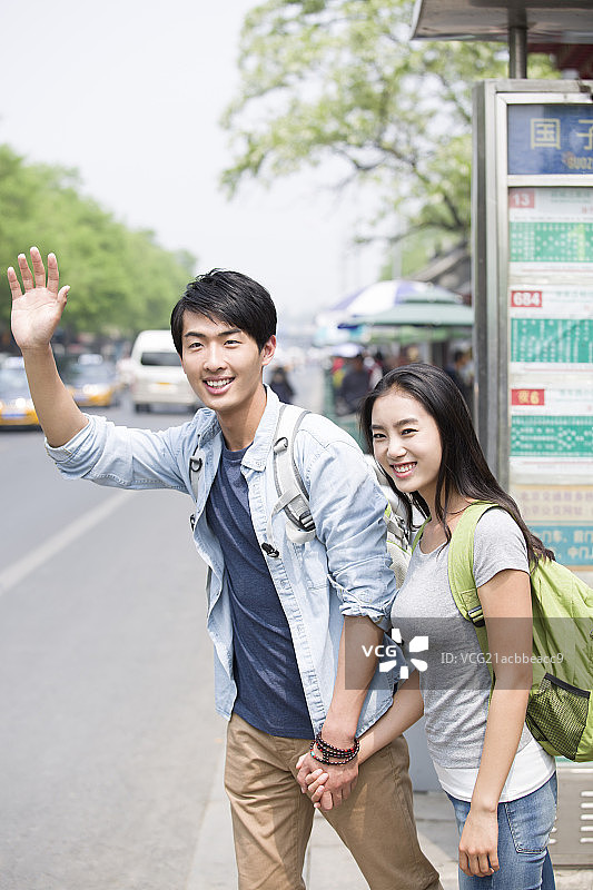 年轻情侣在公交站等车图片素材