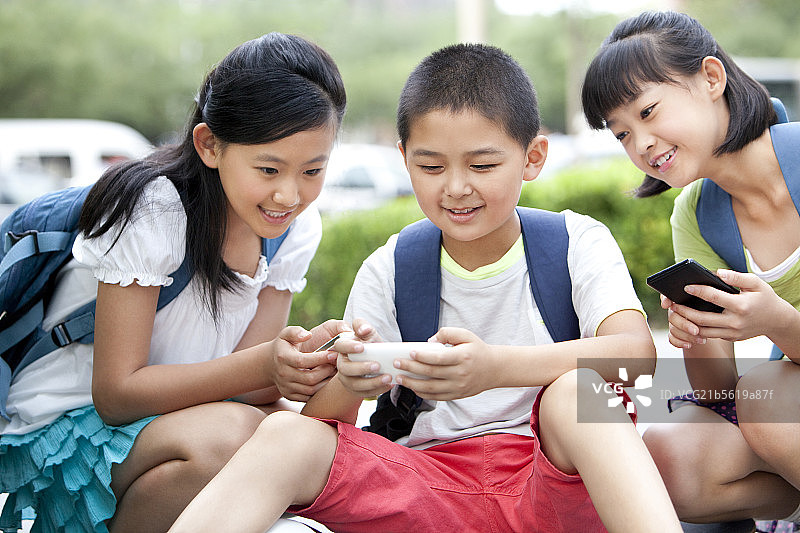 小学生一起玩智能手机图片素材