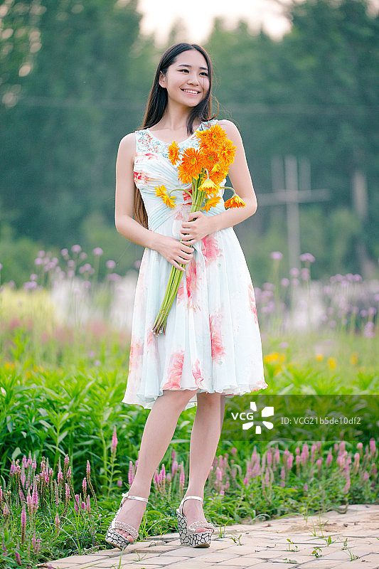 年轻美丽的中国女孩在花园里玩图片素材