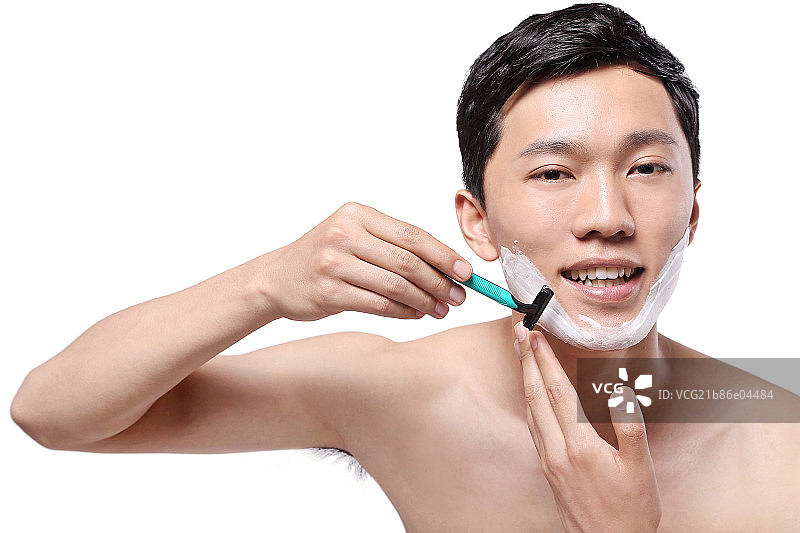 白色背景下面容清爽手拿剃须刀的亚洲男青年图片素材