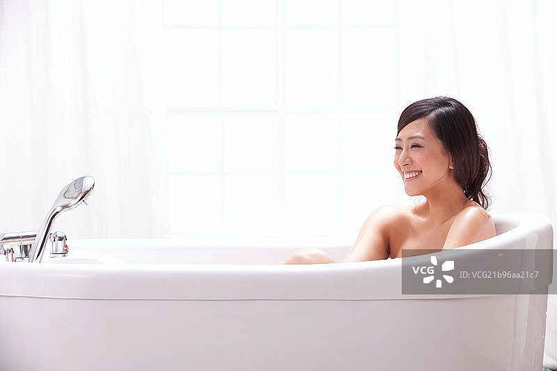 一个年轻女人坐在浴缸中图片素材