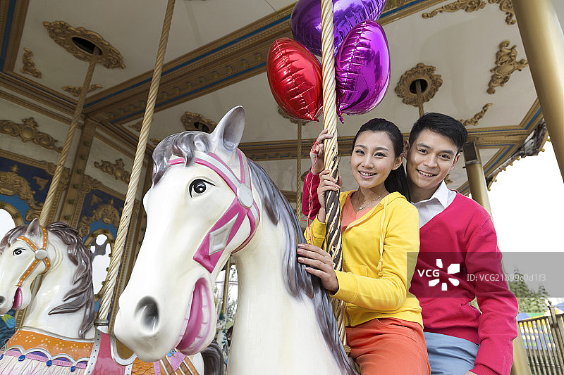 年轻情侣去游乐园骑旋转木马图片素材