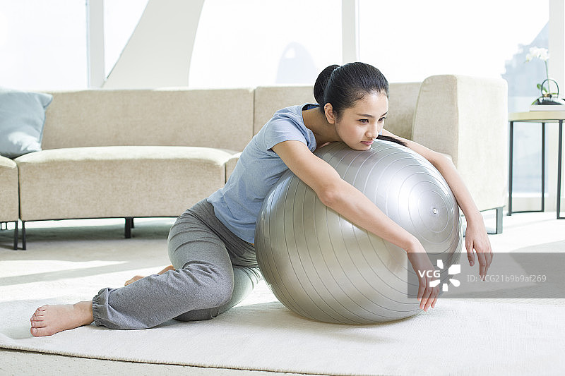 年轻女子趴在健身球上闷闷不乐图片素材