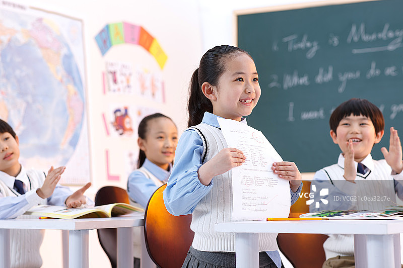 小学生在教室里展示考试卷图片素材