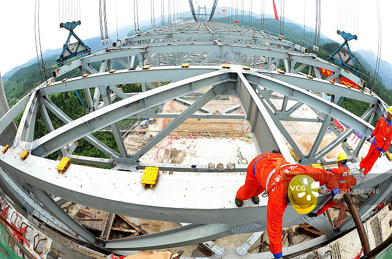 穿着红色工作服戴着黄色安全帽的工人在高架桥上施工图片素材