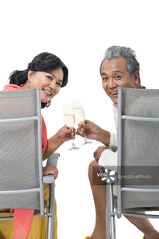 快乐的老年夫妇坐在沙滩椅上喝香槟酒图片素材